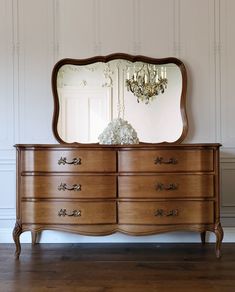 an antique dresser with a large mirror and chandelier on it's side