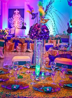 an elaborately decorated table with purple and yellow flowers in a tall vase on it