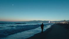 a person standing on the beach at night