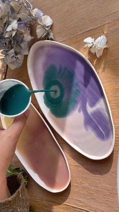 a person is holding a spoon in front of two bowls with flowers on the table