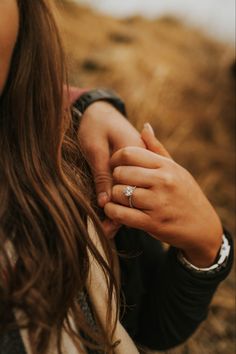 a woman holding the hand of a man who is wearing a diamond ring on his finger