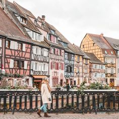 a woman is walking down the street in front of some old buildings with lots of windows