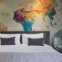 a bedroom with a large wall mural behind the bed and pillows on top of it