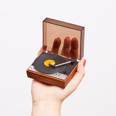 a hand holding a record player with hot dogs on it