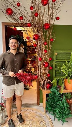 a man standing in front of a christmas tree with decorations on it's branches