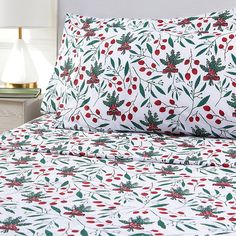 a white bed with red berries and green leaves printed on it, along with two lamps