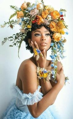 a woman with flowers on her head and hands near her face, posing for the camera