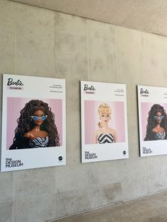 three barbie dolls are displayed on the wall