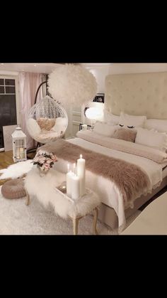 a bedroom with a large bed and white fur on the headboard, two candles in front of the bed