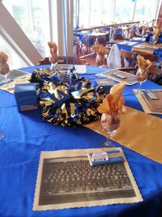 a blue table topped with a laptop computer next to a vase filled with gold ribbon