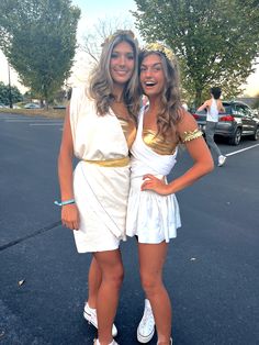 two women dressed up in costumes posing for a photo on the parking lot with their arms around each other