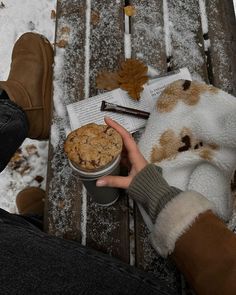 a person sitting on a bench holding a cookie in their hand and reading a book