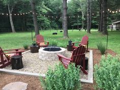 a fire pit surrounded by lawn chairs and string lights in a yard with grass, trees, and bushes