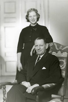 an old black and white photo of two people sitting in a chair with their arms around each other