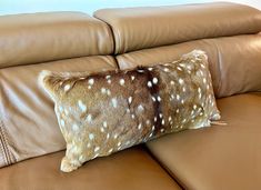 a deer print pillow sitting on top of a brown leather couch