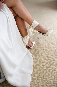 a woman in high heels is sitting on the floor with her wedding dress draped over her