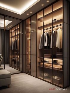 a walk in closet with glass doors and shelves filled with shirts, pants and jackets