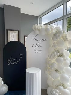 white balloons are on display in front of a sign