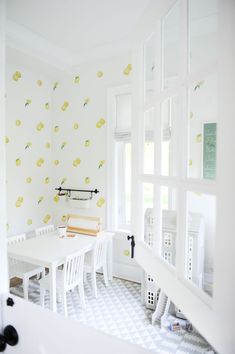 a white dining room with yellow flowers on the wall and table in the middle,