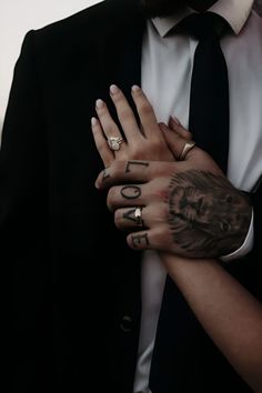 a man and woman with tattoos on their arms holding each other's hands together