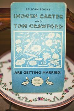 there is a blue book on top of a white plate with flowers and two birds