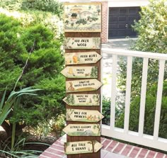 a wooden sign sitting on the side of a building next to a bush and trees