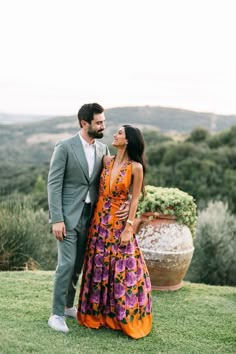 a man and woman standing next to each other on top of a lush green field