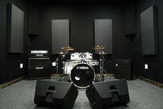 a drum set is shown in the middle of a room with black walls and flooring