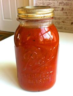 a mason jar filled with tomato sauce sitting on top of a counter