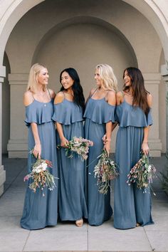 bridesmaids in blue dresses laughing and holding bouquets at the same time as they stand together