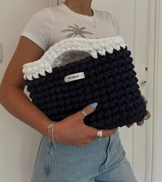 a woman holding a black and white crocheted purse