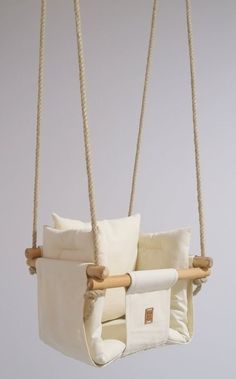 a white swing chair with pillows hanging from it