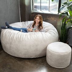 a woman sitting in a bean bag chair next to a potted plant on the floor