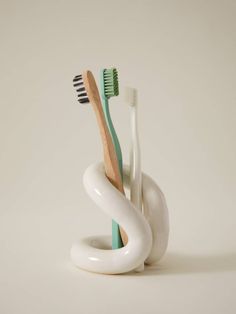 three toothbrushes in a white holder on a white surface with one black and one green