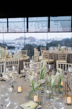 the tables are set for an event with white flowers in vases and place settings