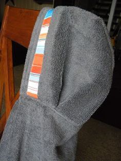 a gray towel with an orange and blue stripe on it sitting on a wooden chair