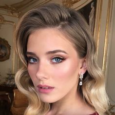 a woman with blonde hair and blue eyes is posing in front of a gold mirror