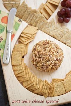 crackers and grapes are arranged on a wooden platter