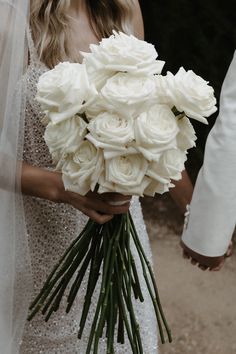 a bride holding a bouquet of white roses