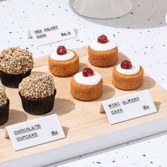 some cupcakes are sitting on top of a wooden board with labels and toppings