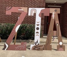 the letters are made out of cardboard and painted pink, brown and white designs on them