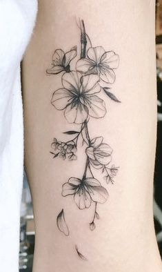 a black and white photo of flowers on the side of a woman's leg