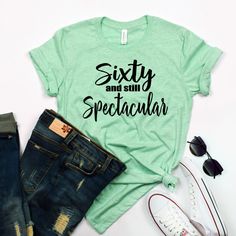 "Sixty and still Spectacular Shirt - Sixty Birthday Shirt - 60th Birthday Shirt - Custom Birthday Shirts - Milestone Birthday Shirts - 60th Sixty and still Spectacular Shirt Adult Unisex Triblend short sleeved Crew Neck. 50% Poly 25% Combed Ring-Spun Cotton 25% Rayon This shirt is Unisex. After making many of these, I am told by multiple people that they fit \"true to size\" . If you like a more \"form fitting\" shirt, I suggest you order a size down. These shirts are Comfy and Soft Wash & C Summer Cotton Tops For Anniversary, Cotton Tops For Anniversary In Summer, Cotton Tops For Summer Anniversary, Casual Short Sleeve Shirt For Anniversary, Casual Cotton Shirt For Anniversary, 60th Birthday Shirt, Sixtieth Birthday, Custom Birthday Shirts, Slouchy Sweatshirt