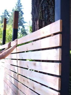 a woman is placing wood on the side of a wooden fence