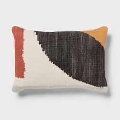 an orange, black and white pillow on a gray background with the same color scheme