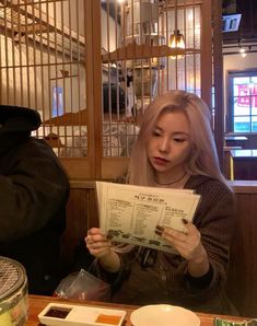 a woman sitting at a table reading a menu