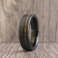 a black ring with gold inlays is on a wooden surface and sits on a table