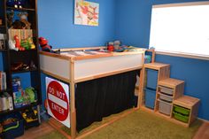 a child's bedroom with blue walls and wooden furniture, including a loft bed