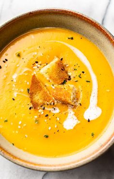 a bowl filled with soup and croutons on top of a white tablecloth