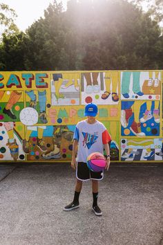 a young man holding a basketball in front of a colorfully painted wall behind him